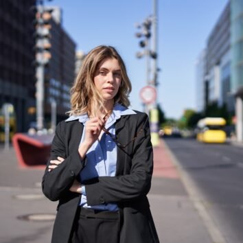 Portrait of confident business woman in suit, cross arms on chest, looking self-assured in city